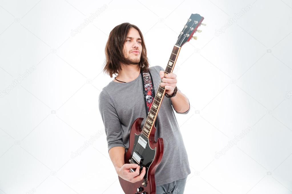 Attractive charismatic male guitarist standing and playing electric guitar