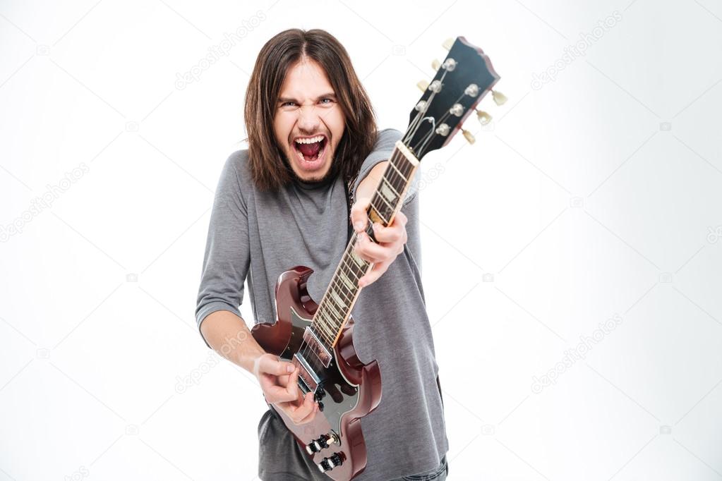 Excited popular young male singer shouting and playing electric guitar