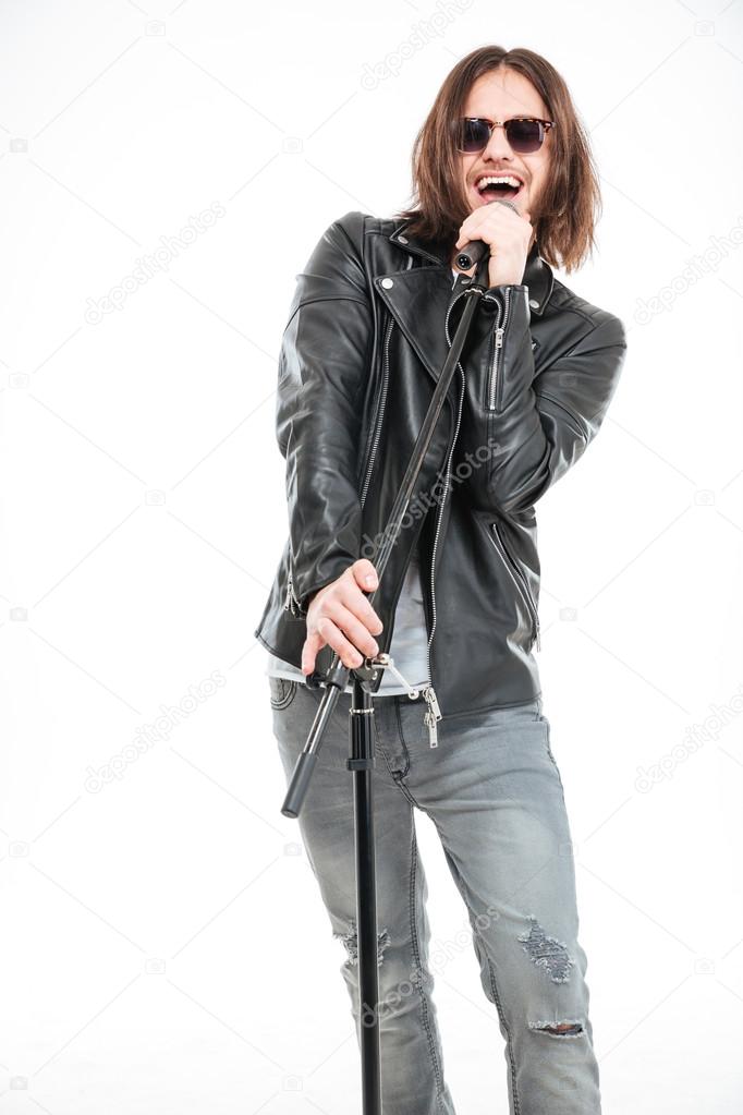 Charismatic male singer in sunglasses standing and singing into micophone