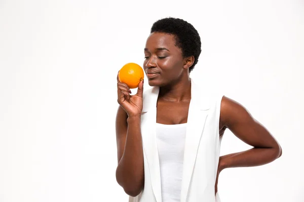 Tender smiling young woman with closed eyes smelling fresh orange — Stock Fotó