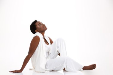 Cute smiling african american young woman sitting and looking up