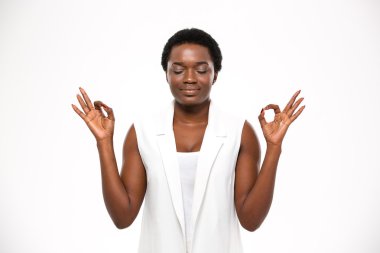 Peaceful attractive african american young woman meditating and keeping calm 