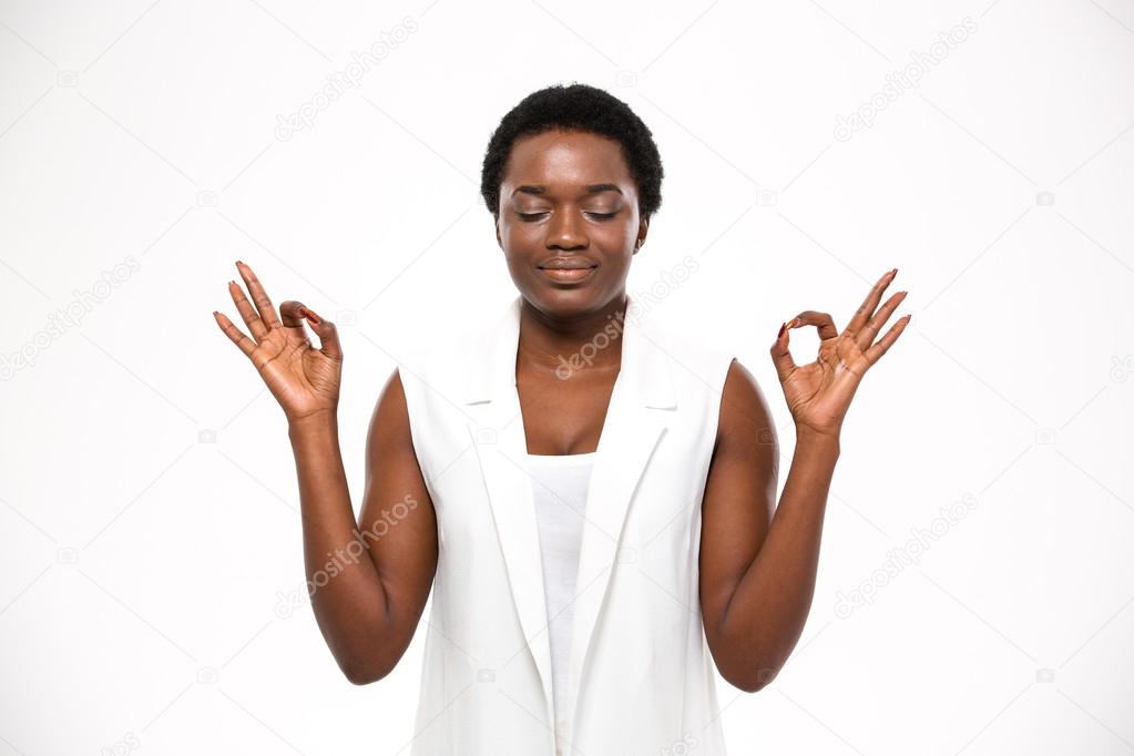 Peaceful attractive african american young woman meditating and keeping calm 