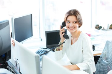 Gülümseyen iş kadını ofiste telefonda konuşuyor