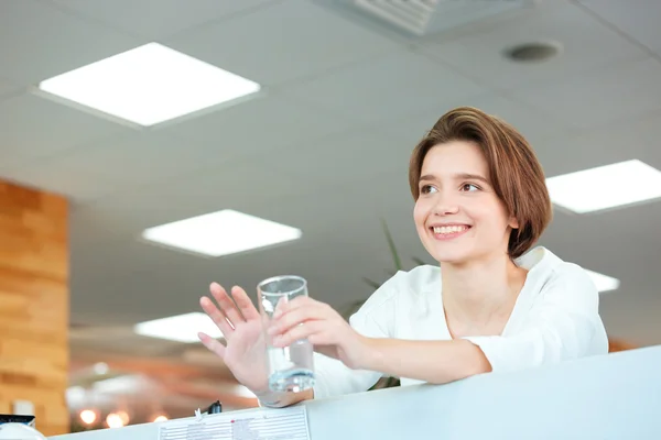 Feliz linda mujer sosteniendo vaso de agua en la oficina —  Fotos de Stock