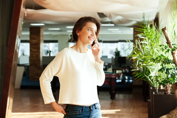 Veselá atraktivní mladá žena mluví na mobilním telefonu v úřadu — Stock fotografie