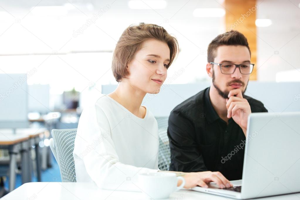 Concentrated young man and woman discussing new project using laptop