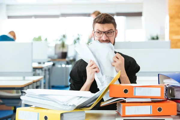 Empresário mordendo papel no escritório — Fotografia de Stock