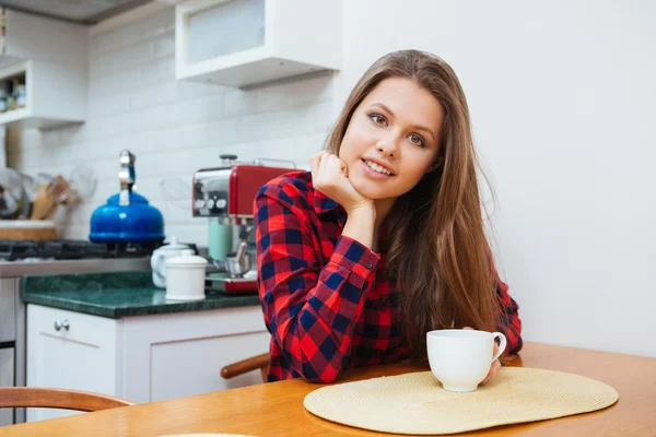 美丽微笑的年轻女子坐在厨房和喝咖啡 — 图库照片
