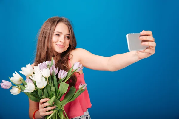 Söt leende ung kvinna med bukett tulpaner med selfie — Stockfoto