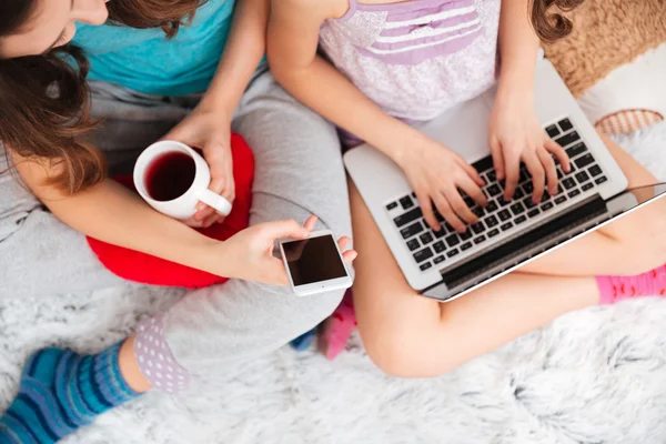 Meninas usando laptop e telefone celular em branco em casa — Fotografia de Stock