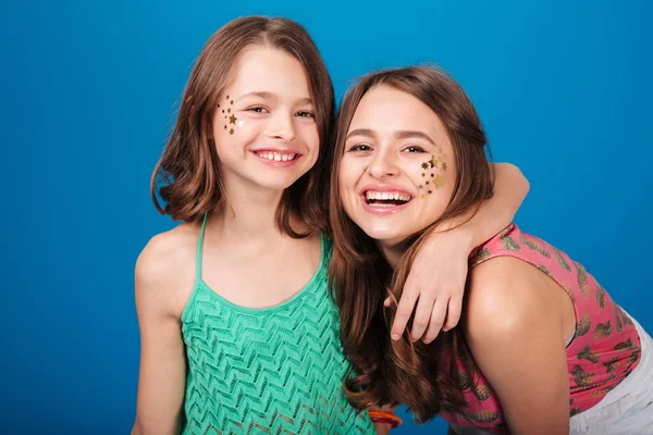 Dvě šťastné krásné sestry s dekoracemi na tvářích smát — Stock fotografie