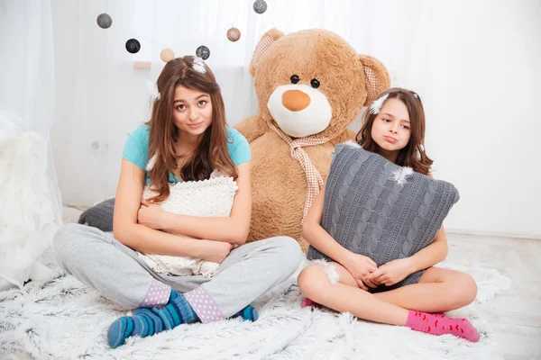 Две грустные уставшие сестры сидят и обнимают подушки — стоковое фото