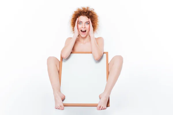 Erstaunt nackte Frau sitzt mit leerem Brett — Stockfoto