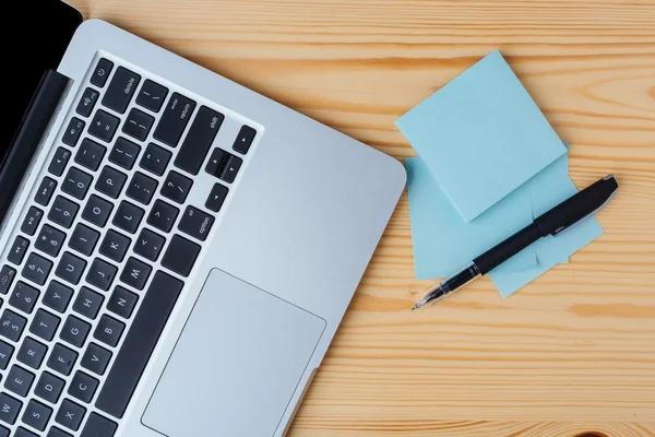 Laptop, bolígrafo y pegatinas en la mesa —  Fotos de Stock