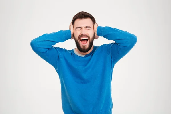 Jonge man die betrekking hebben op zijn oren en schreeuwen — Stockfoto