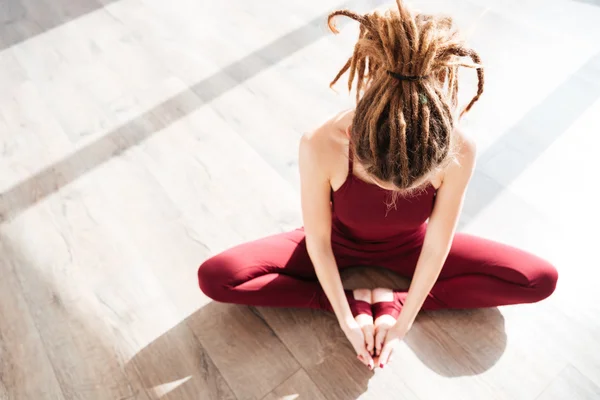 Jeune femme moderne avec dreadlocks assis et faisant du yoga — Photo