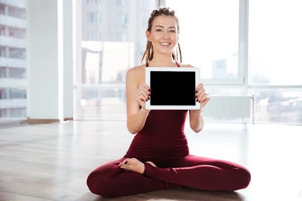 Šťastná žena, sedící v józe pozice zobrazeno prázdnou obrazovku tabletu — Stock fotografie