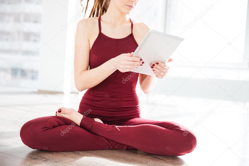 Pretty young woman dancer sitting and using tablet