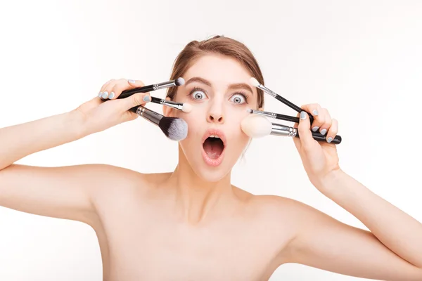 Retrato de belleza de la joven divertida sorprendida con pinceles de maquillaje —  Fotos de Stock