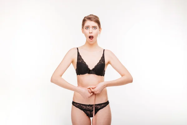 Shoked bela jovem mulher em lingerie rendas medindo sua cintura — Fotografia de Stock