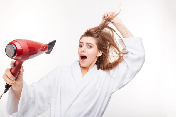 Funny frightened young woman drying hair and scared of dryer — Stock Photo, Image