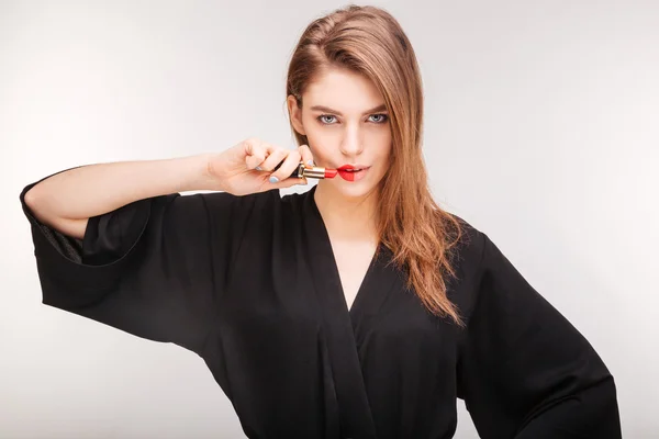 Gorgeous woman demonstrating red lipstick on half of her lips — 스톡 사진
