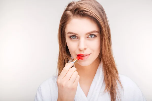 Pretty smiling young woman using lipstick on half of lips — Stock Fotó