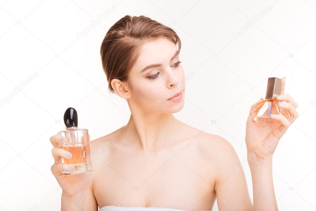 Attractive young woman holding two bottles of parfums 