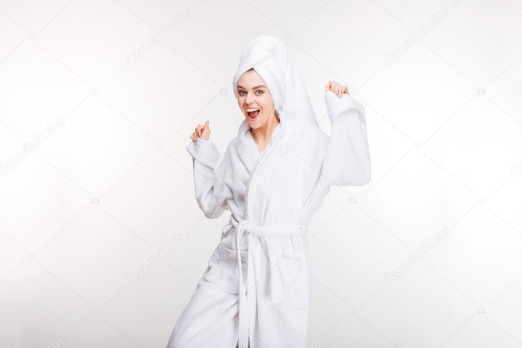 Happy excited woman dancing in bathrobe with towel on head 