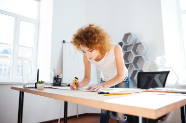 Serious woman photographer with curly red hair working in office