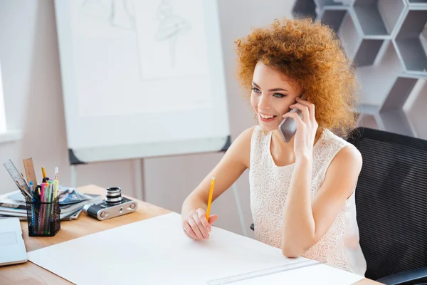 Alegre hermosa fotógrafa sentada y hablando en el teléfono móvil — Foto de Stock