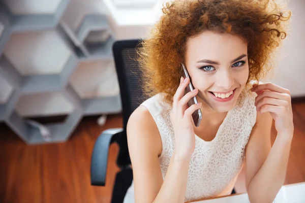 Smiling beautiful business woman talking on mobile phone at workplace — Stok Foto