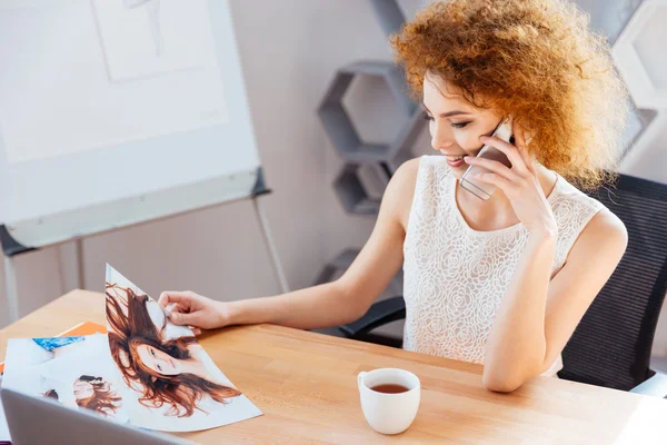 Happy woman photographer talking on cellphone and looking at photos — Stock Photo, Image