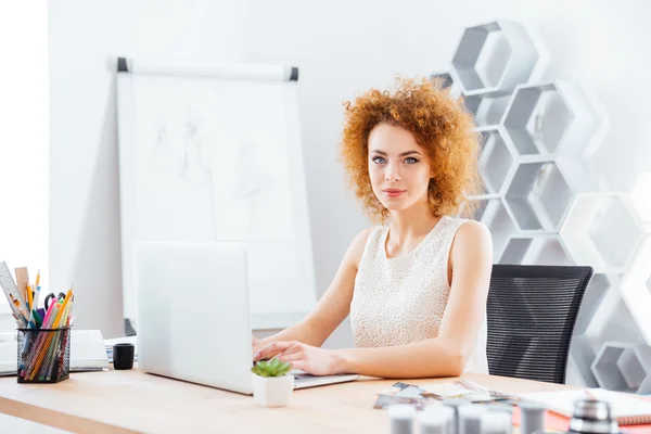 Красивая уверенная женщина модельер с помощью ноутбука в офисе — стоковое фото