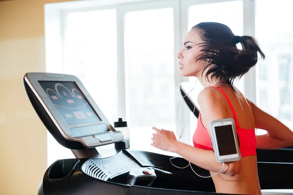 Frau läuft im Fitnessstudio auf Laufband und hört Musik — Stockfoto