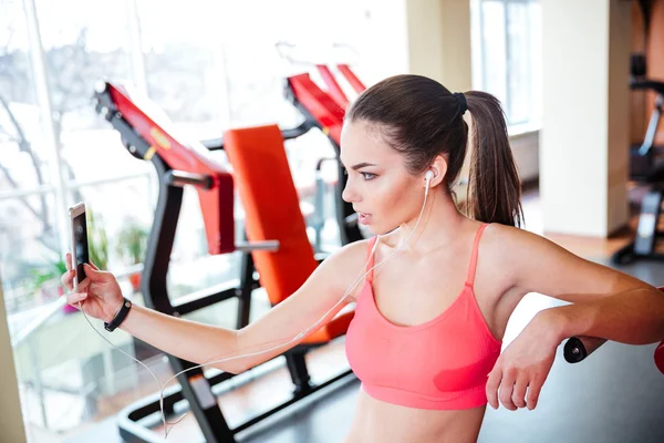 Mujer atleta tomando selfie y escuchando música en el gimnasio —  Fotos de Stock