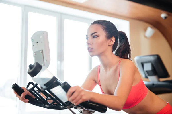 Schöne Sportlerin trainiert auf dem Fahrrad im Fitnessstudio — Stockfoto