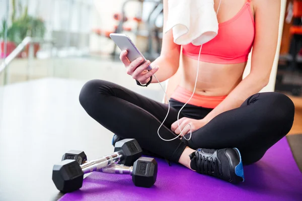 Mujer atleta sentada y usando el teléfono móvil en el gimnasio —  Fotos de Stock