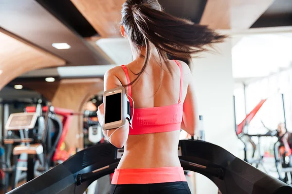 Vrouw atleet met balnk scherm smartphone draait op loopband — Stockfoto