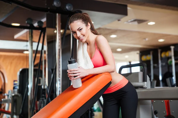 Gelukkig Sportvrouw met flesje water op de opleiding in de sportschool — Stockfoto