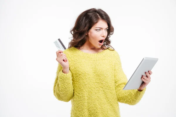 Shocked woman holding credit card and tablet computer — Stock Photo, Image