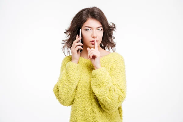 Woman talking on the phone and showing finger over lips — Stock Photo, Image