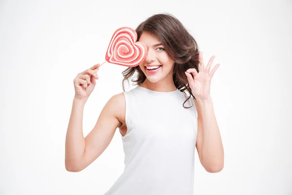 Leende kvinna håller lollipop och visar ok tecken — Stockfoto