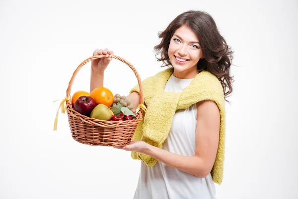 Mulher sorridente segurando cesta com frutas — Fotografia de Stock