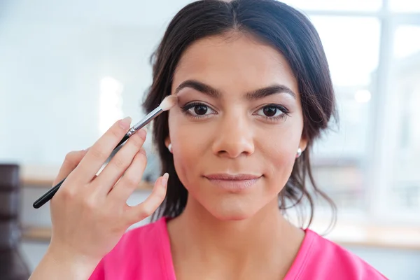 Mano de mujer visagista aplicando sombra de ojos a modelo bastante joven — Foto de Stock