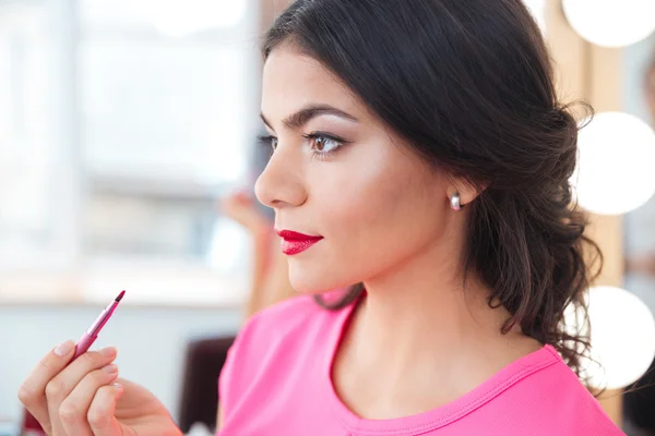Pretty young woman putting on red lipstick — Stock Photo, Image