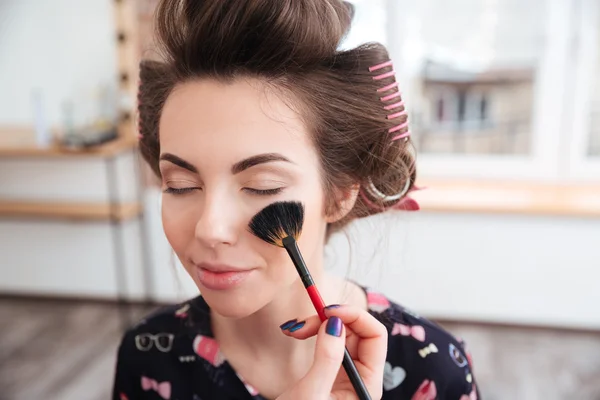 Makeupartist tillämpa borste för ansikte av kvinna i papiljotter — Stockfoto