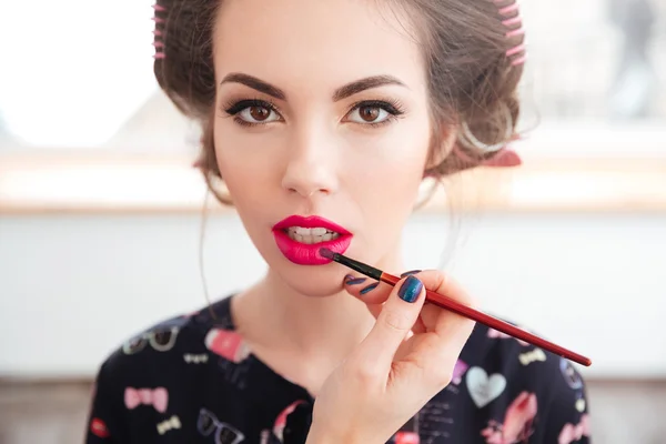 Makeup artist applying pink lipstick and brush to young woman — Stock Photo, Image