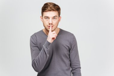 Gri kazak sessizlik jest gösterilen yakışıklı genç adam